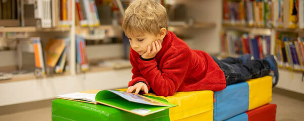 Un enfant en train de lire dans une bibliothèque