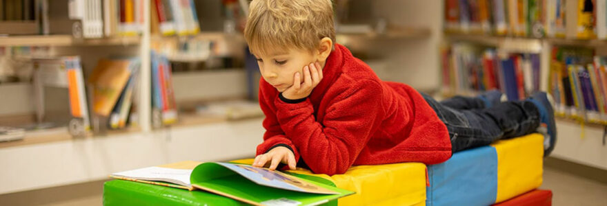 Un enfant en train de lire dans une bibliothèque